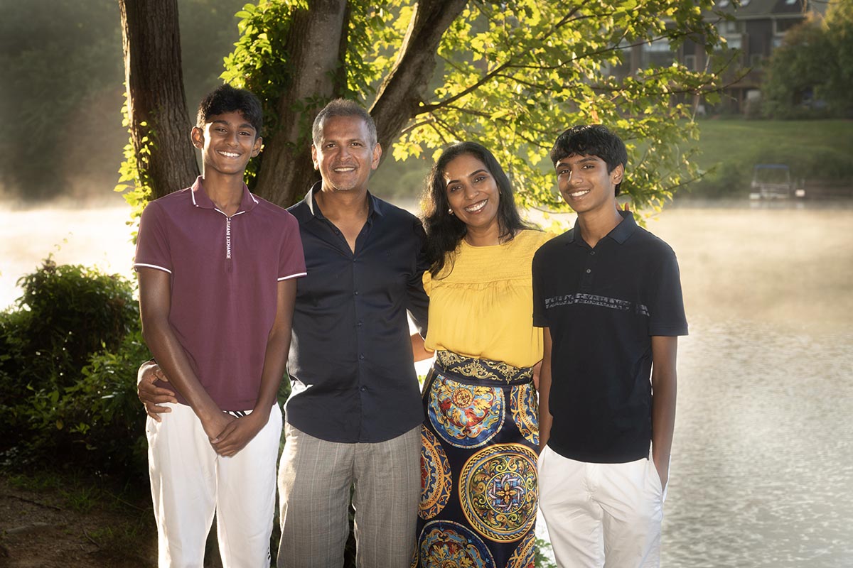 Dr. Archana Srinivasan of Ateeth Dental Care in Reston, VA, standing outdoors with her family, smiling and enjoying a beautiful, sunny day by the water.