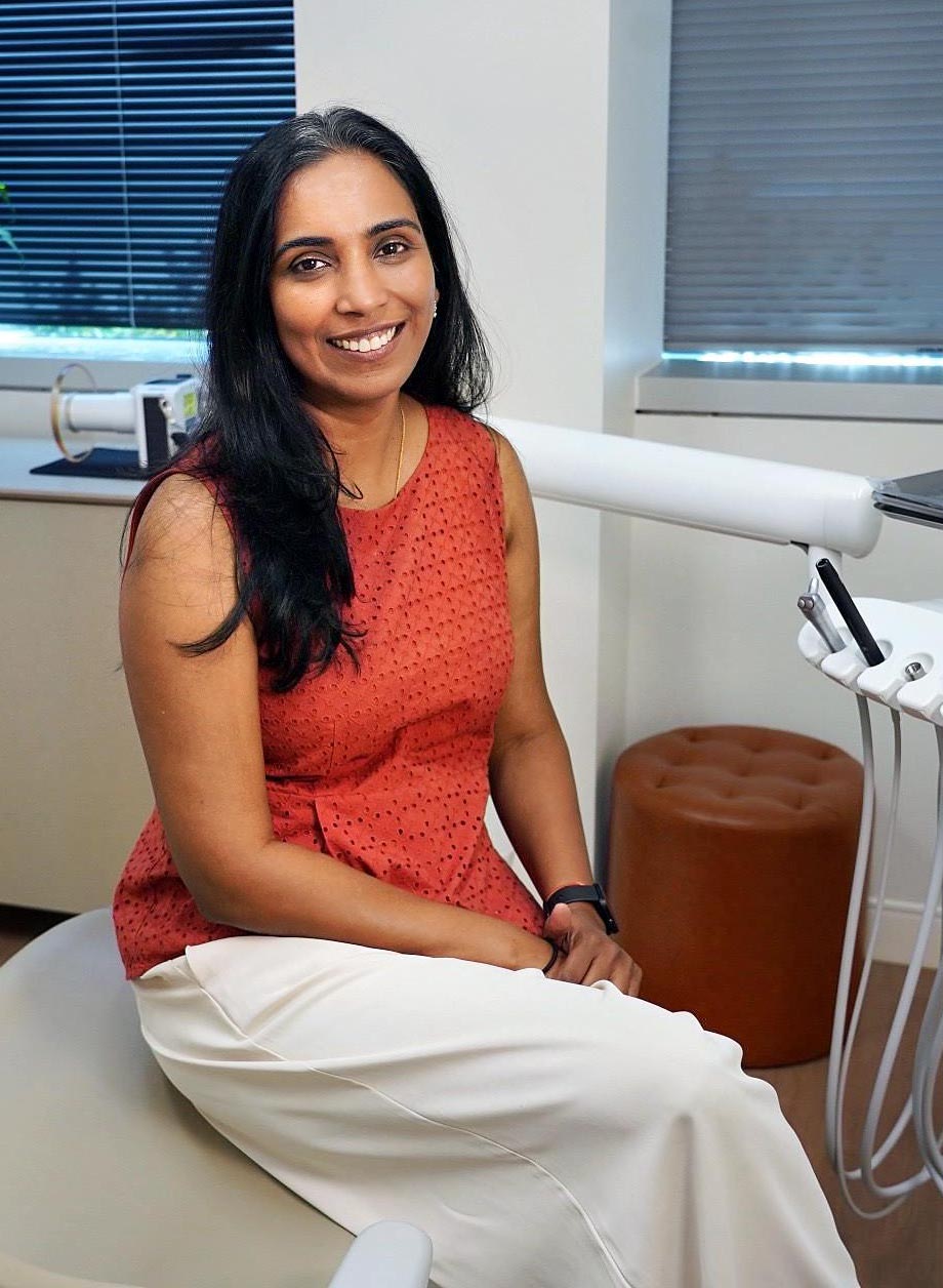 Dr. Archana Srinivasan, dentist and founder of Ateeth Dental Care in Reston, VA, sitting in a modern dental treatment room, exuding warmth and professionalism.